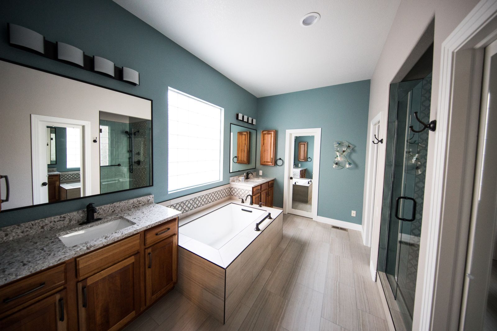 A remodeled bathroom with a soaking tub, twin vanities, and a glass shower