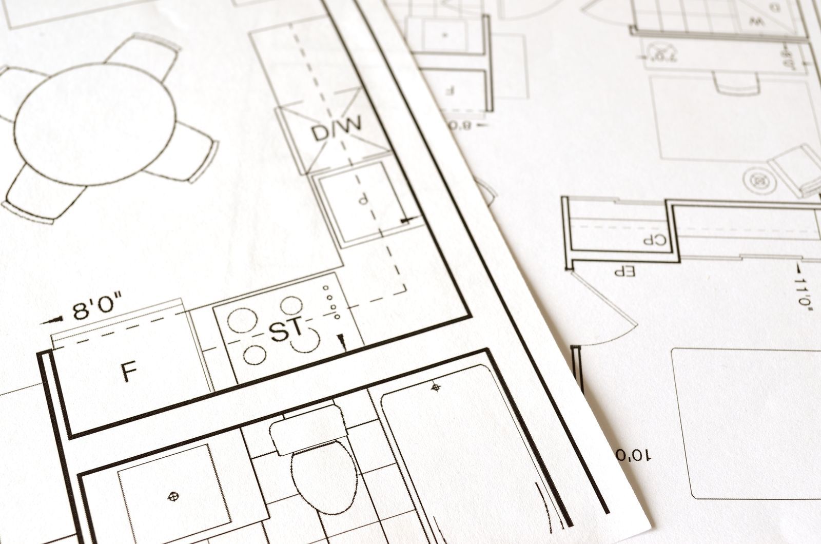 Residential floor plans with imperial dimensions spread on a table