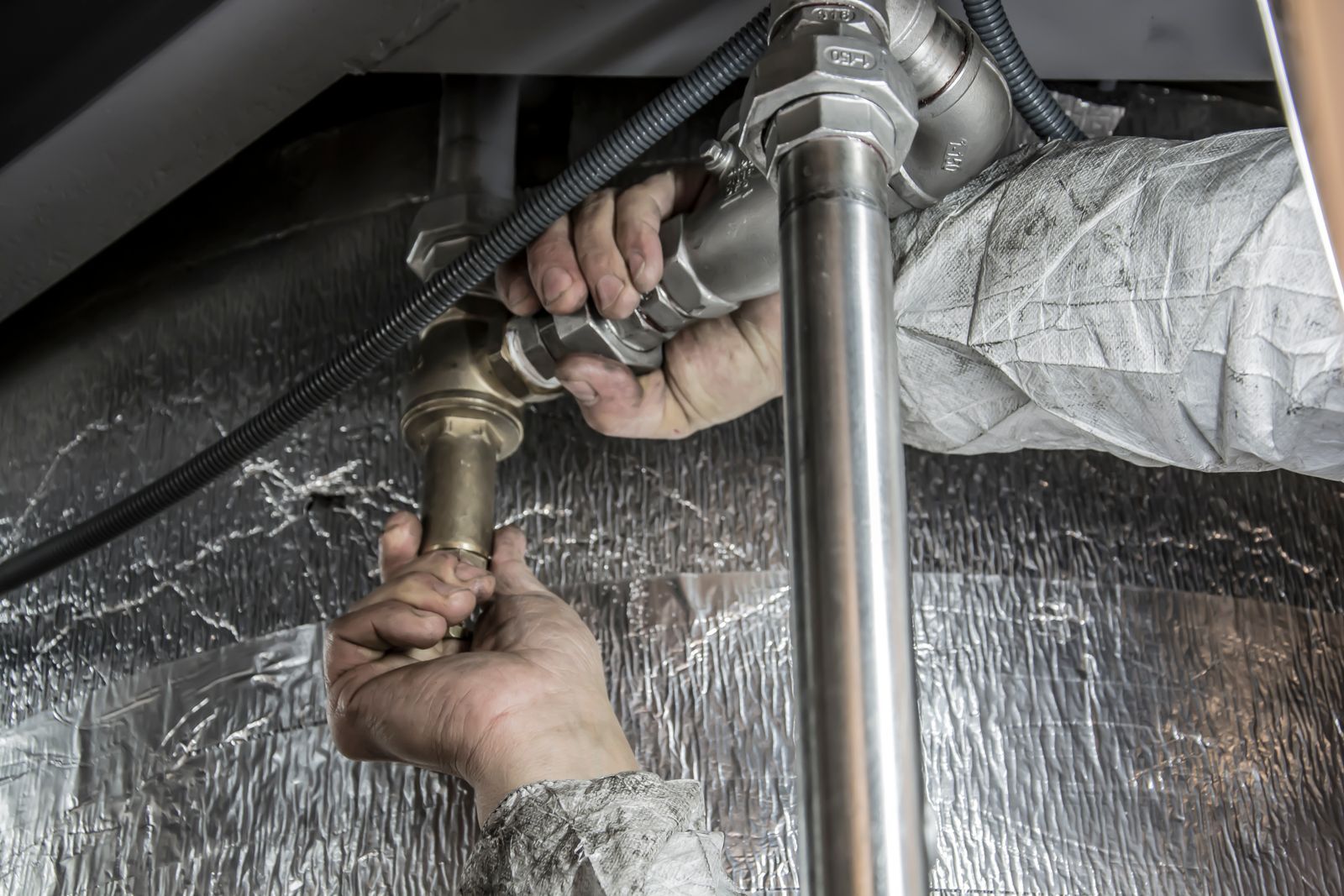 A plumber tightens a fitting on water supply pipes