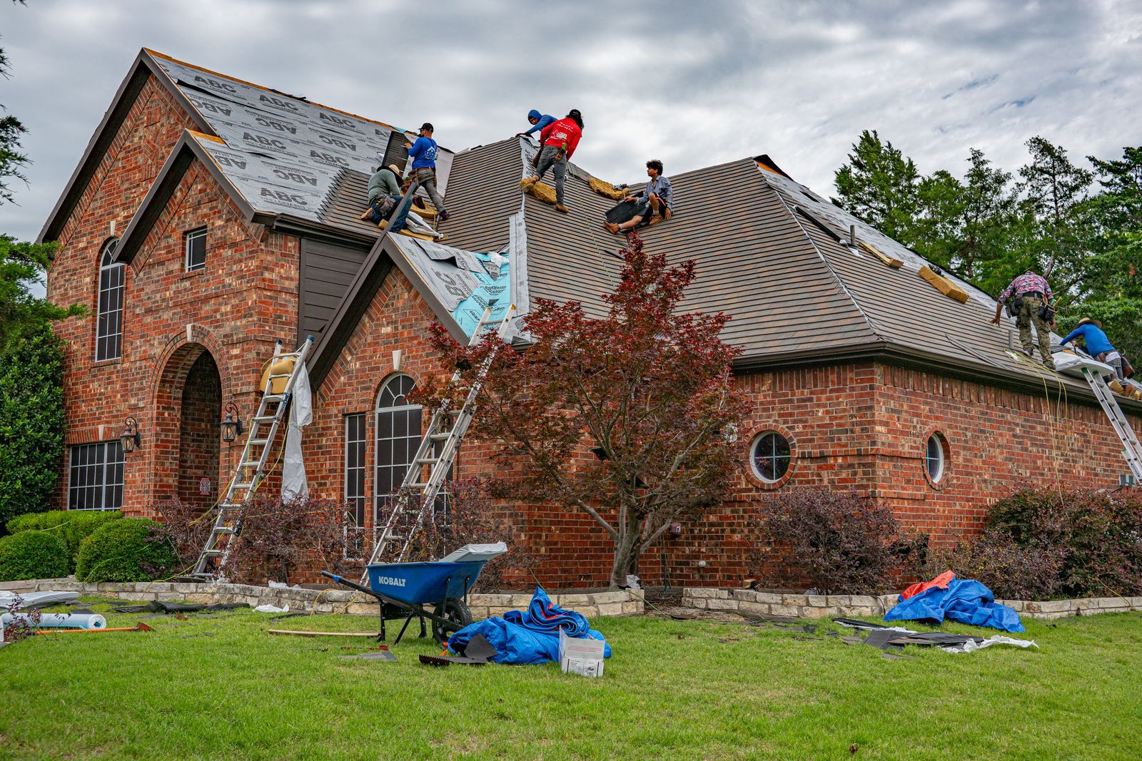 A roofing crew replaces the shingles on a brick house