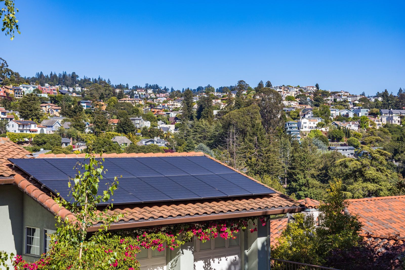 Rooftop solar panels on a tile-roofed house in a hillside neighborhood